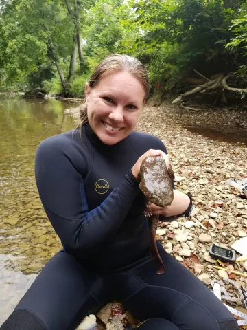 Photo of Sarah Tomke and an aquatic salamander species, Eastern hellbender